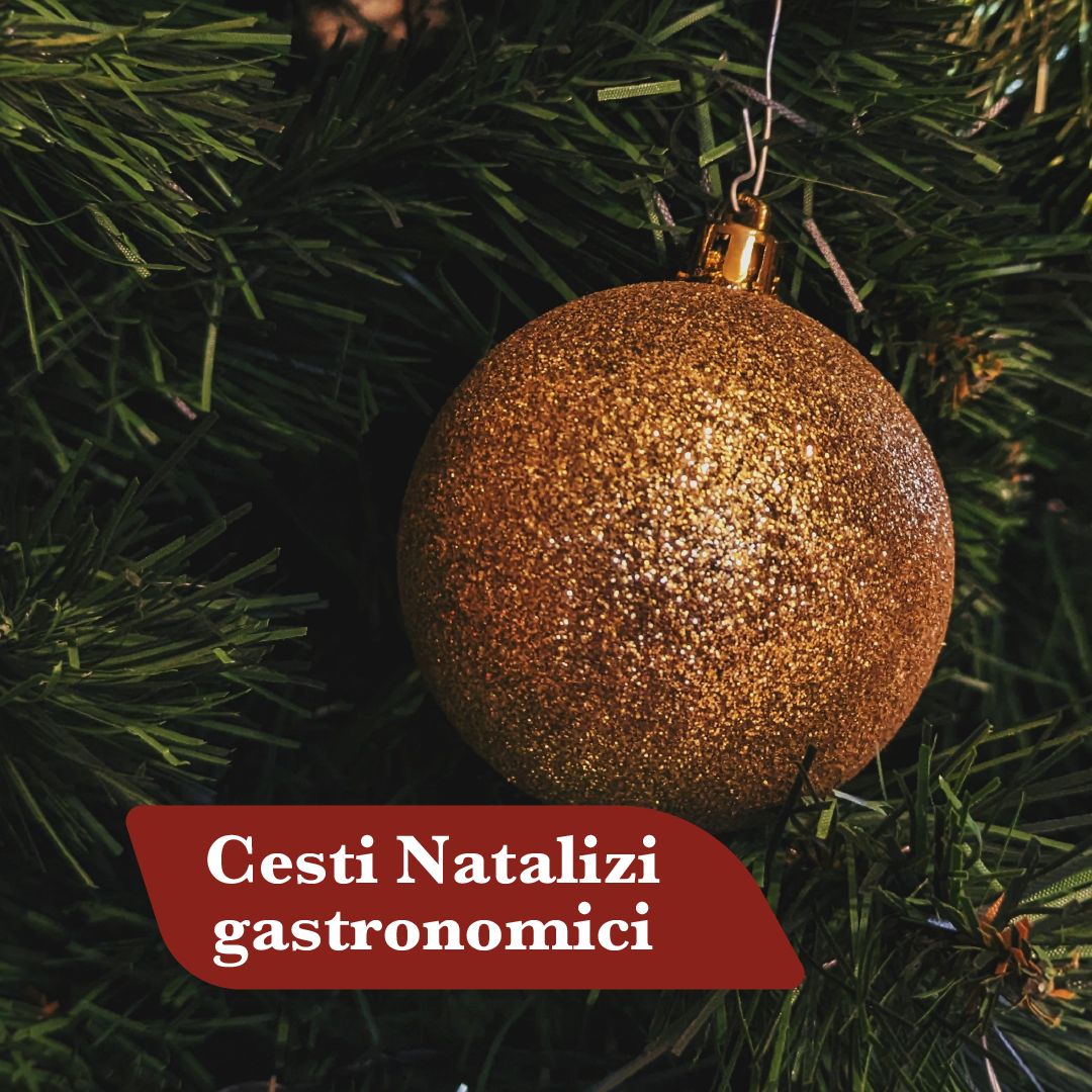 Cesti natalizi gastronomici: pallina di Natale dorata su rami di abete