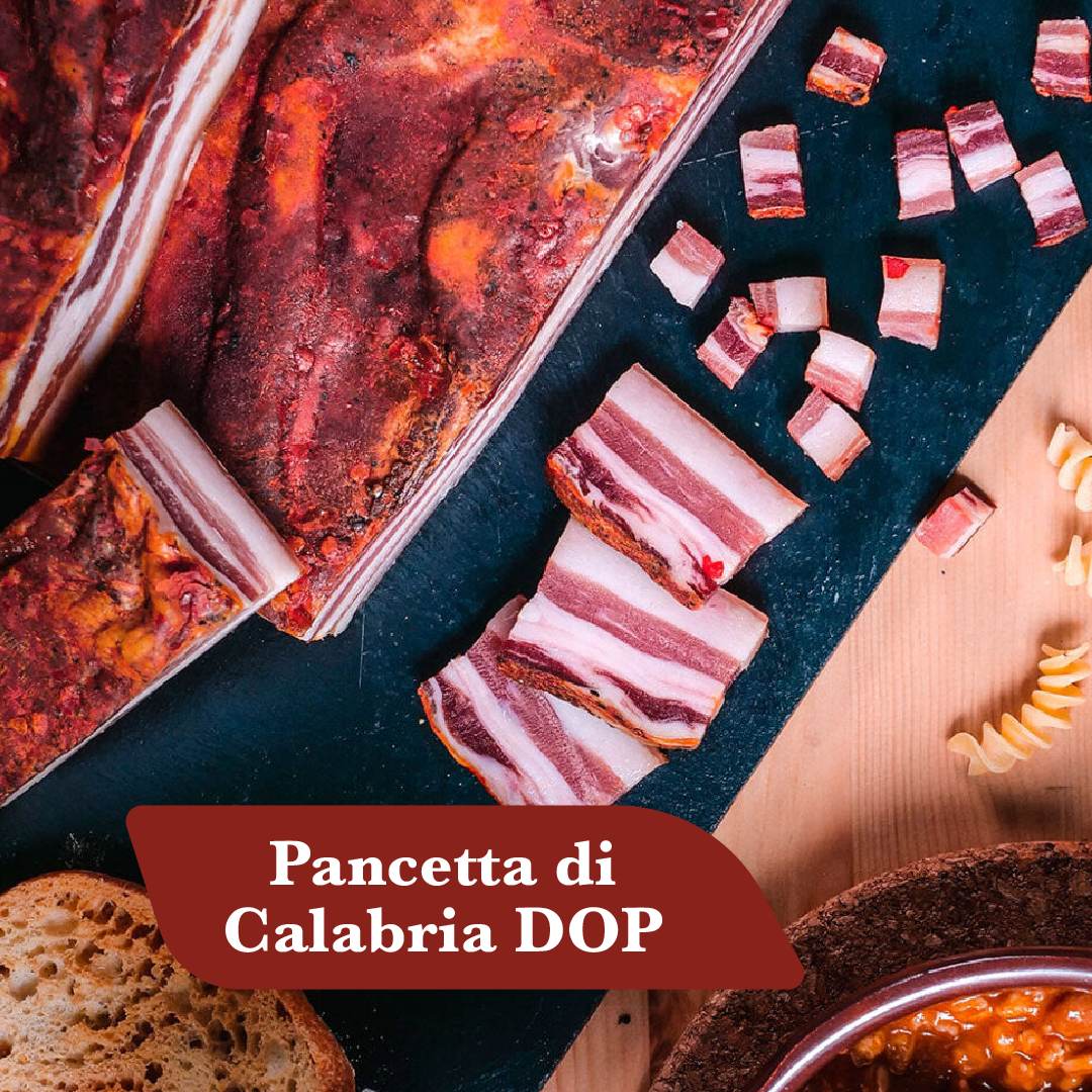 Pancetta di Calabria DOP: trancio di pancetta calabrese con peperoncino, fette e cubetti su ardesia