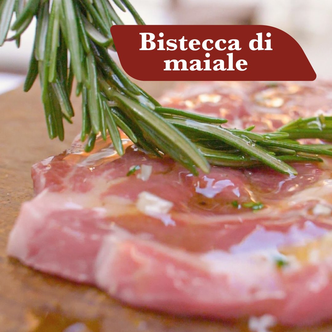 Bistecca di maiale cruda con rosmarino, aglio e olio pronta per la griglia
