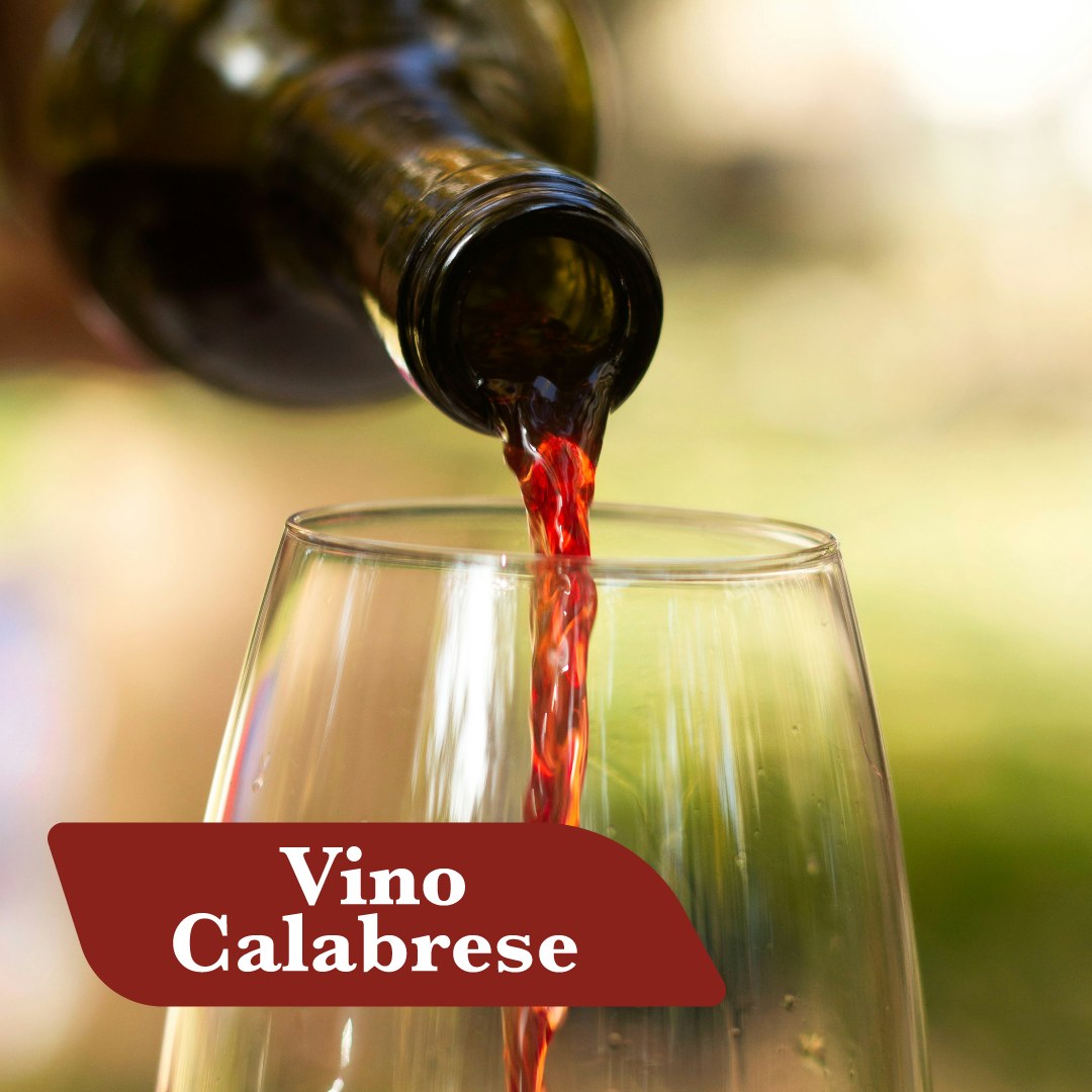 Vino calabrese rosso versato dalla bottiglia nel calice